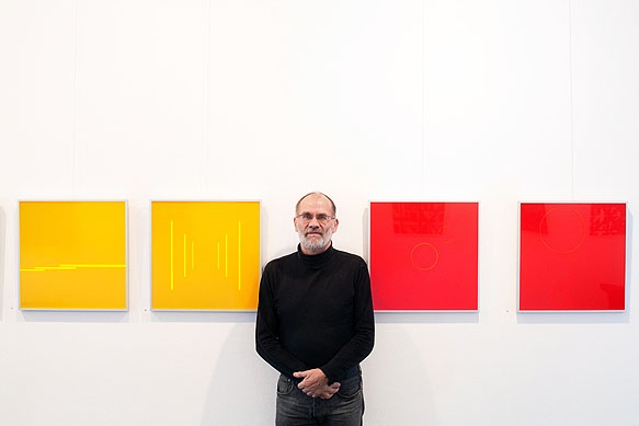 Galerist Eberhard Klinger zwischen Bilder der Ausstellung Konkrete Spektrale